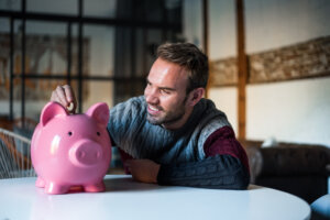 Guía para ahorrar con ingresos irregulares y estabilizar tus finanzas 2 happy young man with saving piggy bank